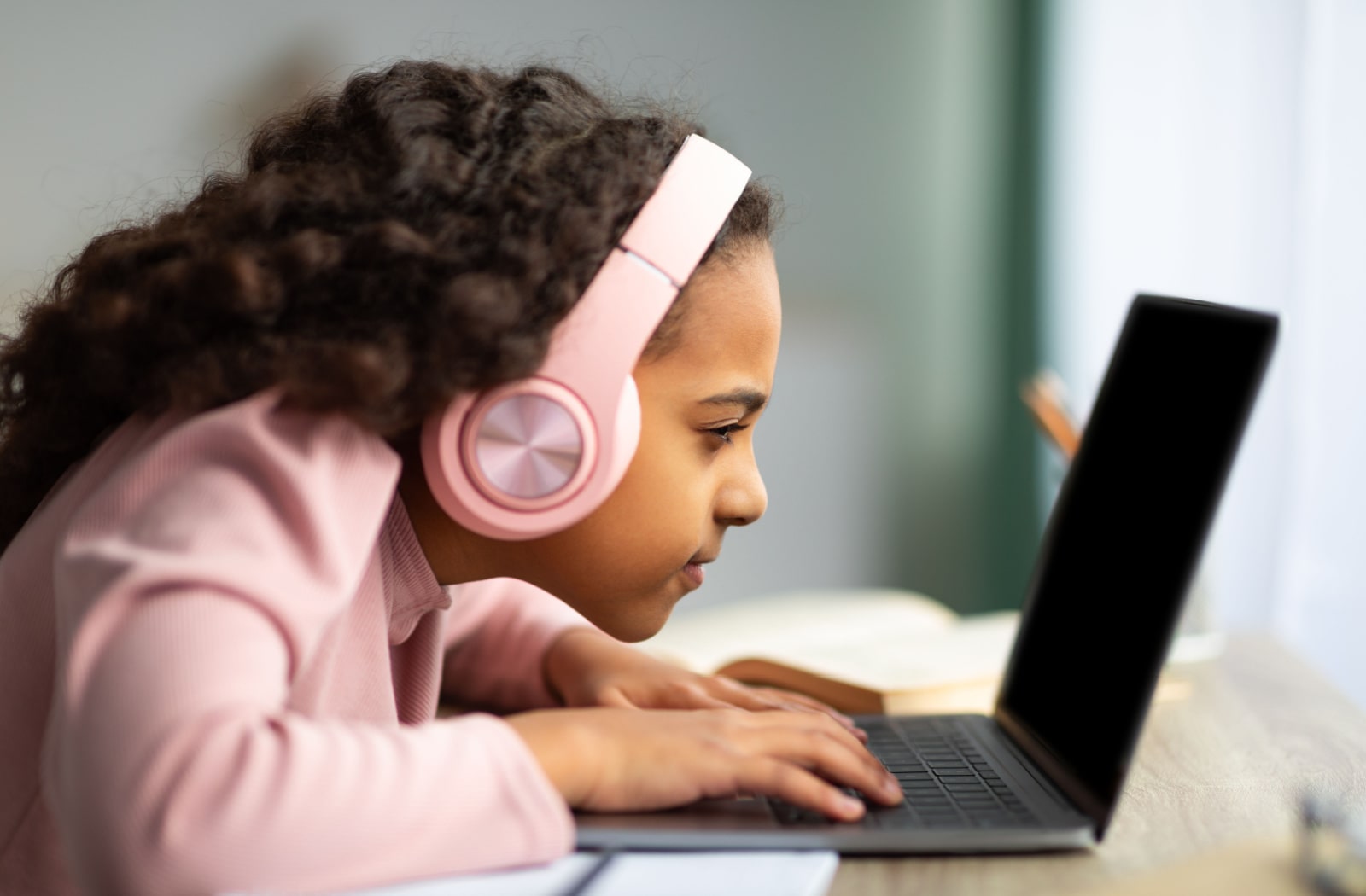 A young girl is sitting in front of her computer laptop and facing to close on the computer screen.