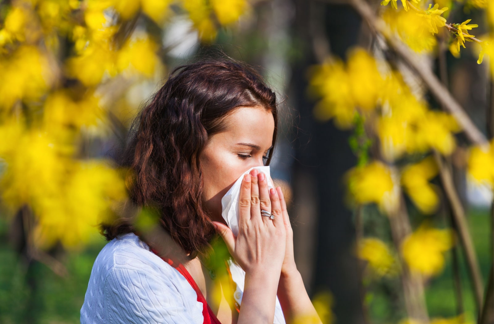 A woman blowing her nose due to seasonal allergies
