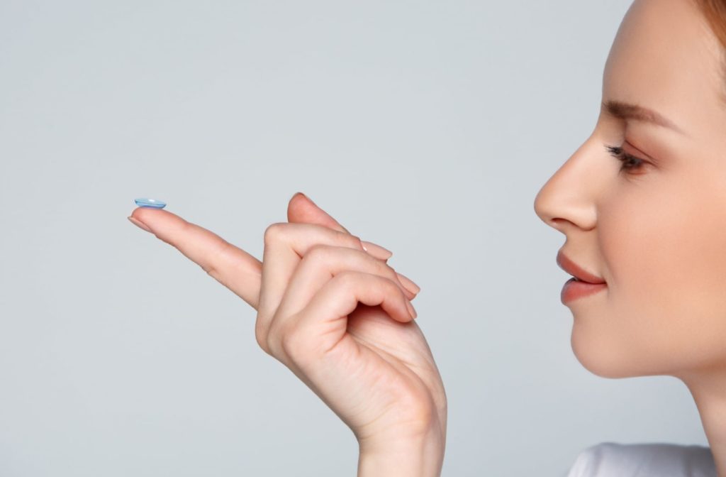 A woman holding onto a contact lens with her index finger as she looks at it.