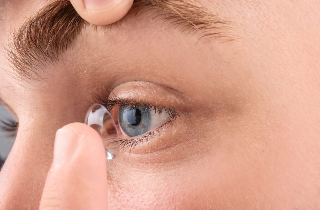 A close-up image of someone putting a daily disposable contact lens onto their eye.
