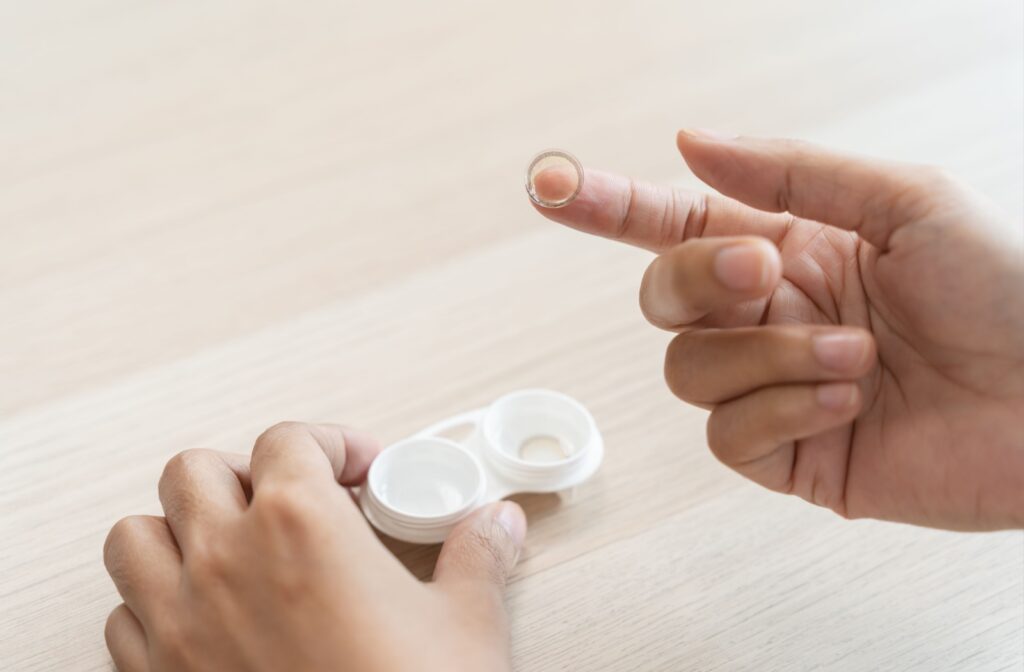 Close-up of a person's hands with a contact lens resting on their index finger.